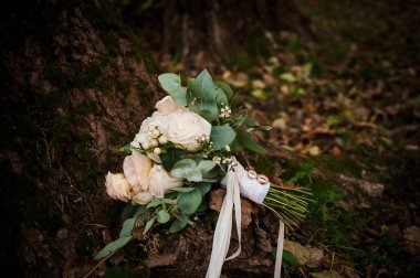 Bir buket beyaz çiçekte bir çift altın alyans. Bir buket gülün üzerinde altın yüzükler