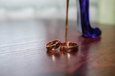 Kahverengi arka planda bir çift altın alyans.