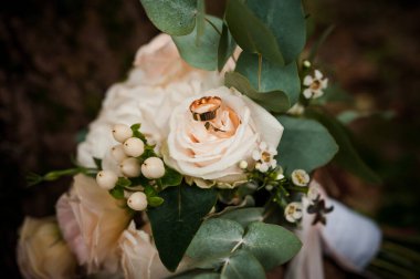 Bir buket beyaz çiçekte bir çift altın alyans. Bir buket gülün üzerinde altın yüzükler