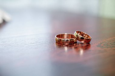 Kahverengi arka planda bir çift altın alyans.