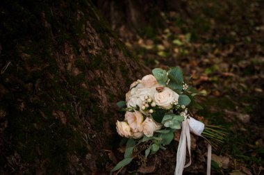 Bir buket beyaz çiçekte bir çift altın alyans. Bir buket gülün üzerinde altın yüzükler