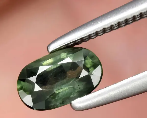 natural dark green sapphire gem on background