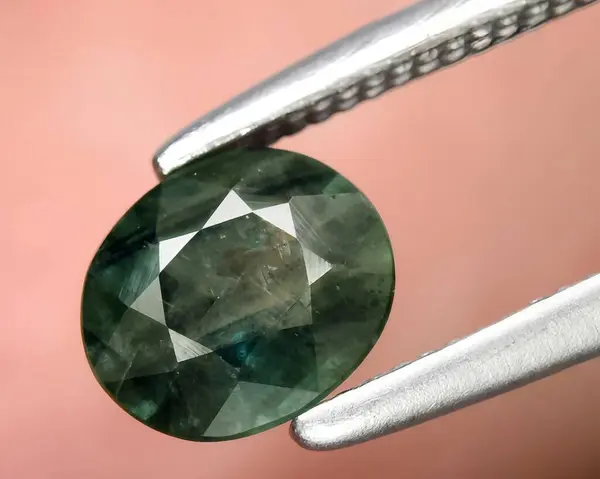 natural dark green sapphire gem on background
