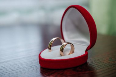 Alyanslar kahverengi arka planda kırmızı kalp şeklinde bir kutuda.