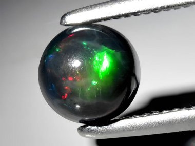Arka planda doğal gökkuşağı siyah opal değerli taşı