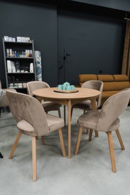 Sarı ahşap masa, bej ahşap koltuklar ve yumuşak kumaş döşeme. Masada mavi porselen bir çaydanlık ve mavi kupalar var.