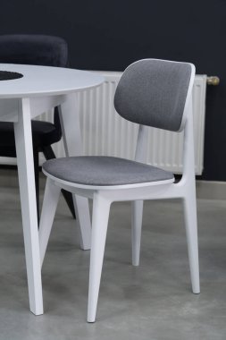 Beyaz ahşap masa, yumuşak kumaş döşemeli siyah ve beyaz sandalyelerle tamamlanmış. Masadaki siyah mum..