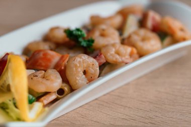 Limonlu karides salatası bej arka planda beyaz bir tabakta
