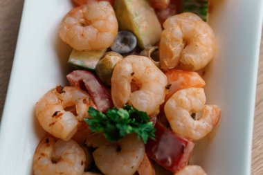 Limonlu karides salatası bej arka planda beyaz bir tabakta