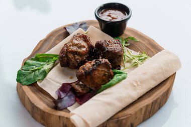 Beyaz arka planda ahşap bir tahtada soslu domuz bifteği.