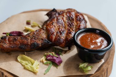 Beyaz arka planda ahşap bir tahtada soslu domuz bifteği.