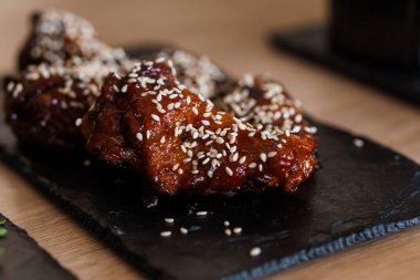 Siyah tahtada susam tohumlu soya balı tavuk kanadı.