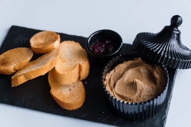 Soslu börek ve beyaz arka planda siyah tahtada kızarmış ekmek.