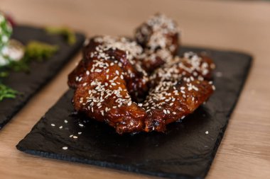 Siyah tahtada susam tohumlu soya balı tavuk kanadı.