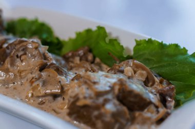 Beyaz tabakta sebzeli ve mantarlı haşlanmış et.