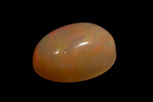 stock image natural rainbow opal gem isolated on the black background