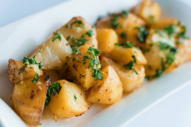 Sert peynirli patates, bir tabakta salatalık ve otlar.