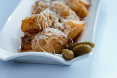 Sert peynirli patates, bir tabakta salatalık ve otlar.