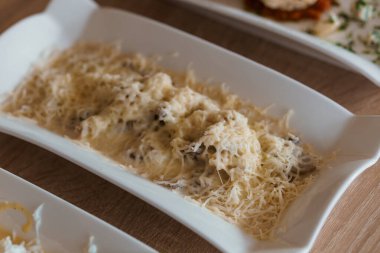 Sert peynirli patates, bir tabakta salatalık ve otlar.