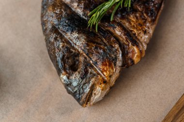 Ahşap bir tahtanın üstünde ızgarada limon ve biberiyeyle pişirilmiş Dorado balığı