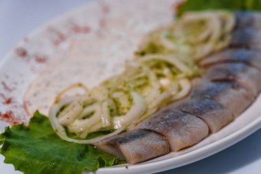 Turşulu yeşil soğan ve soslu ringa balığı.