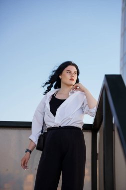 Siyah pantolonlu ve beyaz gömlekli bir iş kadını. Bir iş merkezinin geçmişine karşı siyah takım elbiseli bir iş kadını.