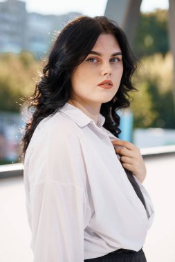 Beyaz bluzlu bir iş kadınının portresi. Beyaz gömlekli bir iş kadını portresi, arka planda bir iş merkezi var.