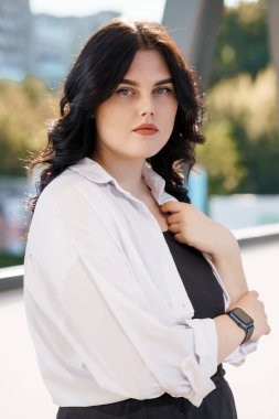 Beyaz bluzlu bir iş kadınının portresi. Beyaz gömlekli bir iş kadını portresi, arka planda bir iş merkezi var.