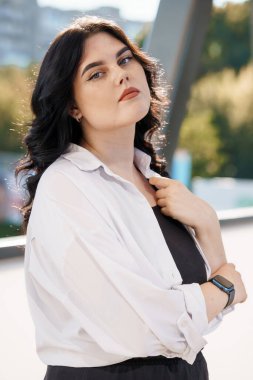 Beyaz bluzlu bir iş kadınının portresi. Beyaz gömlekli bir iş kadını portresi, arka planda bir iş merkezi var.