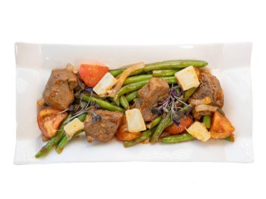 Gurme Lamb ve Yeşil Fasulye Salatası ile Feta ve Taze Domatesler Zarif Beyaz Tabakta.