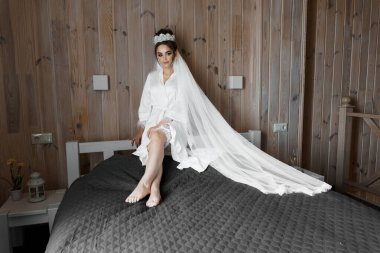 Lüks Gelinlikli Zarif Gelin Kırsal Ahşap İç dekorasyonda Zarif Bir Yatakta Oturuyor.