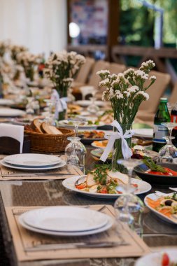 Dekoratif çiçek süslemeleri ile lüks bir etkinlik için şık bir açık hava yemek masası seti..