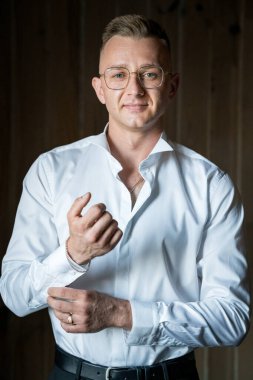 Kendine güvenen adam beyaz gömleği sofistike bir şekilde ayarlıyor..