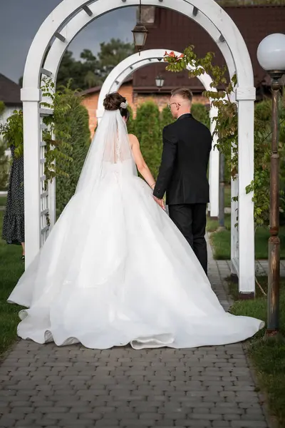 stock image Enchanting Garden Wedding - Bride and Groom Strolling under Charming White Arches.