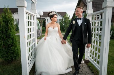 Zarif Açık Hava Düğün Töreni: Bir Gelin ve Damat Manzaralı Bahçede Neşeli Yürüyüş.