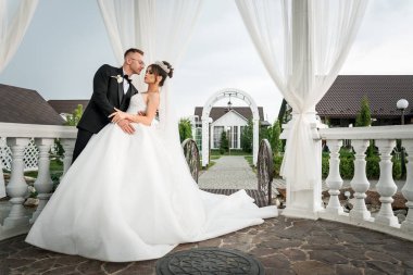 Romantik Düğün Çifti Sahne Bahçesi 'nde Zarif Beyaz Drapery Altında Kucaklaşıyor.