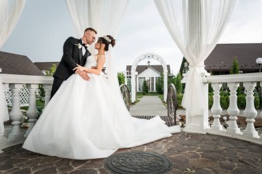 Idyllic Açık Hava Düğün Ayarlarında Romantik Gelin ve Damat Şık Örtü Altında Kucaklaşır.