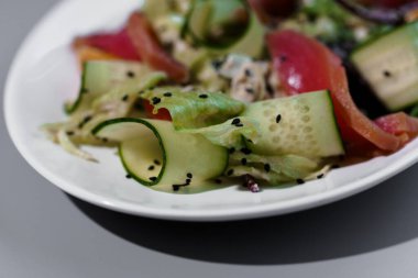 Beyaz tabakta siyah susam tohumlu taze ve canlı salatalık..