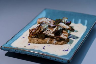 Krem soslu gurme ızgara mantarlar. Süslü mavi seramik tabakta sanatsal kaplama..