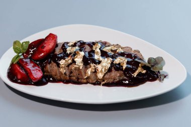 Altın Yapraklı Gurme Biftek ve Beyaz Tabakta Böğürtlen Sosu.