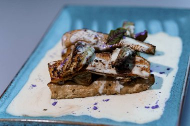 Gurme Sanatı: Sütlü Mor Garnitürlü Kremalı Mantar Mantarı Zarif Mavi Tabakta.