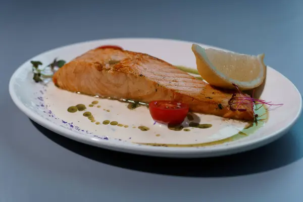 stock image Gourmet Presentation of Grilled Salmon Fillet with Creamy Sauce and Fresh Garnish on Elegant White Plate.