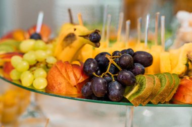 Cam bir tabakta zarif bir şekilde yerleştirilmiş taze meyve çeşitliliği..