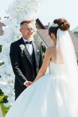 Gelin ve Damatla Romantik Açık Hava Düğün Töreni Çiçek Kemerinden Önce Duruyor.