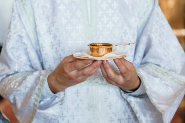 Clerical Hands Holding Golden Chalice in Spiritual Ceremony. clipart