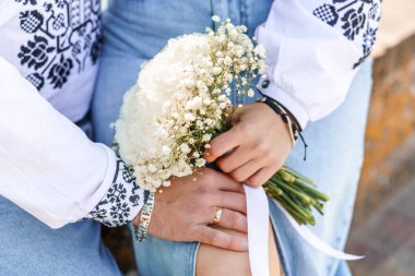 Şefkatli Kucaklaşma: Geleneksel Giyimde Güzel Çiçek Buketiyle Romantik Bir An.