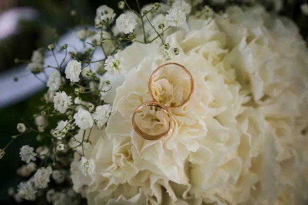 Zarif alyanslar Süslü beyaz çiçekle süslenir Hassas çiçeklerin arasında.