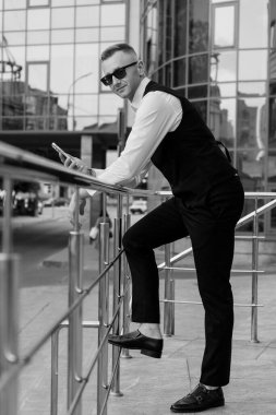 İş dünyasındaki şık genç adam açık havada kendine güvenle poz veriyor..