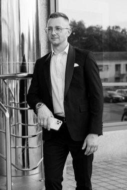 Modern bir binanın dışında kendine güvenen şık giyimli bir adam..