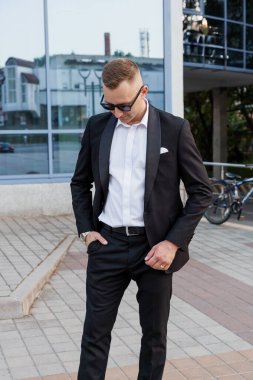 Şehir merkezinde güneş gözlüklü, siyah takım elbiseli şık bir beyefendi..